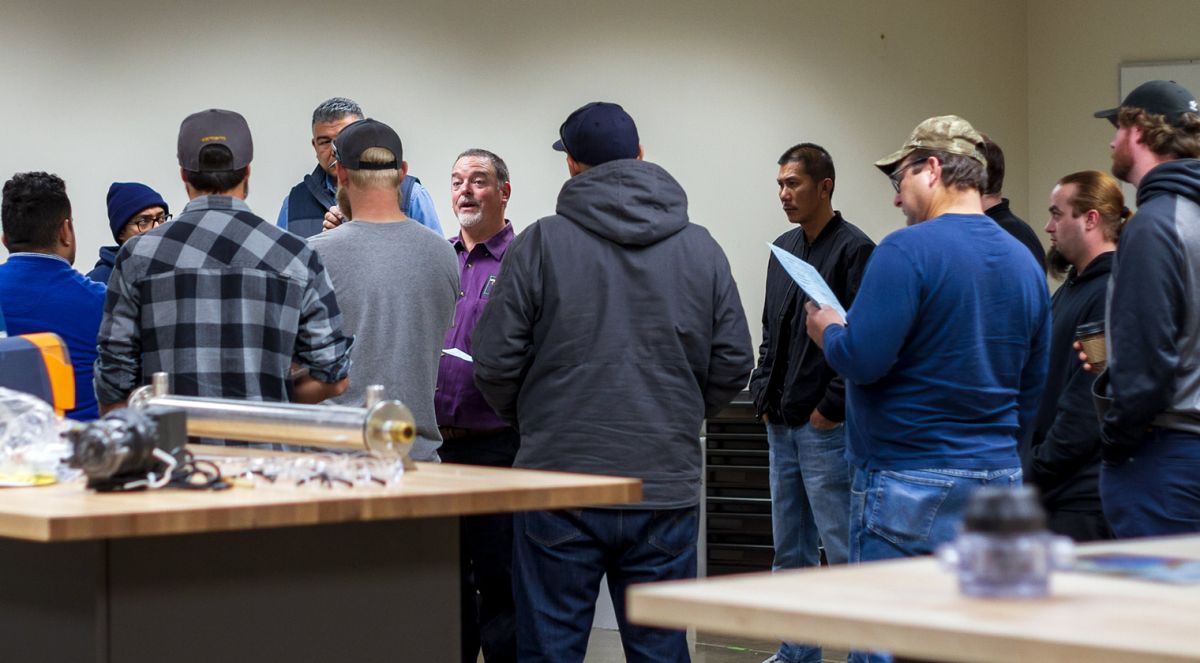 A group of apprentices stand with their instructor for a demonstration. 